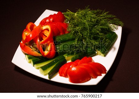 plate with different fresh vegetables tomatoes,cucumbers,pepper and greens. the concept of healthy organic food