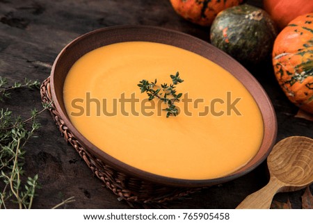 Pumpkin puree soup with thyme on a dark wooden background