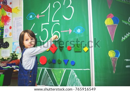 First grade boy at school, showing numbers and calculating in front of the blackboard