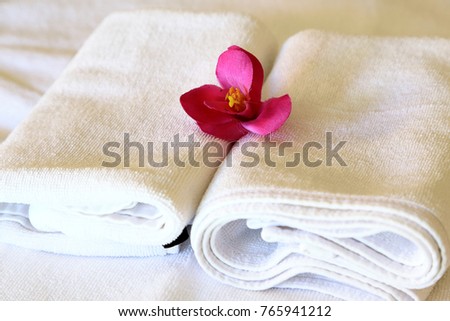 Close-up of White spa towels with pink flowers on bed, as background spa wellness concept.