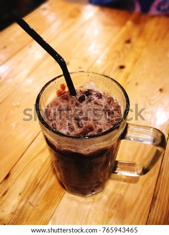 Iced cocoa drinks in a glass on wooden background.