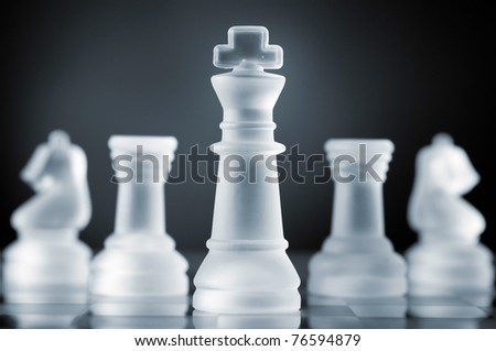 glass chess pieces is standing on board in dark