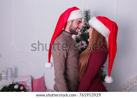 A guy with a girl are standing next to each other looking at the background of a Christmas tree