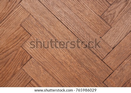 Part of the parquet in a natural wood texture laid out on the floor like a herringbone