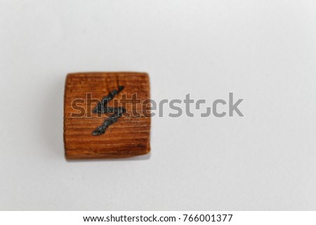 Wooden rune which means Sun lie on a table on a white background