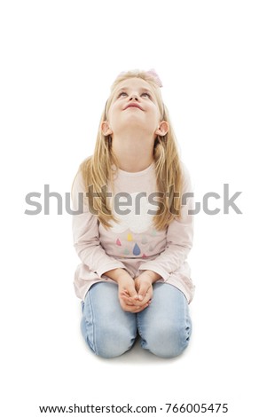 Portrait of a cute girl sitting on the knees, looking up. Isolated on white background