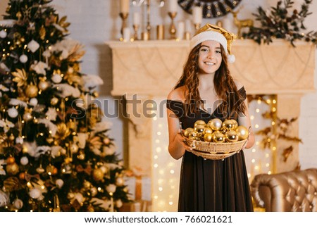 beautiful young girl in santa cap holding basket with golden balls