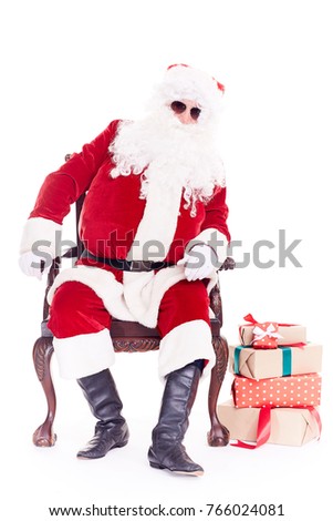 Portrait of swaggy Santa Claus in sunglasses relaxing in chair on white background