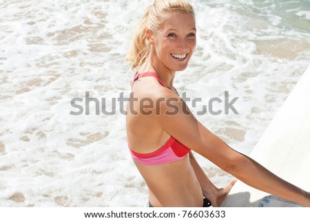 happy young attractive woman holds a surfboard ready to go to the water