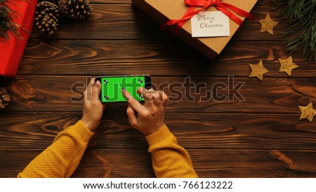 Woman hands in yellow sweater using black smart phone, Christmas atmosphere, green screen, chroma key, tracking motion, top view
