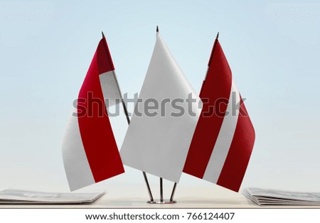 Flags of Monaco and Latvia with a white flag in the middle