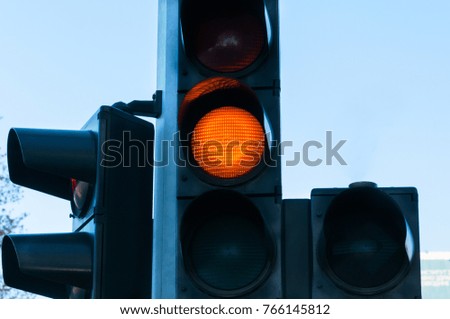 Orange traffic light for vehicles on the crosswalk close up