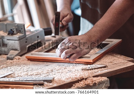 The carpenter in the workshop makes frames for paintings with the help of hand tools. Royalty-Free Stock Photo #766164901