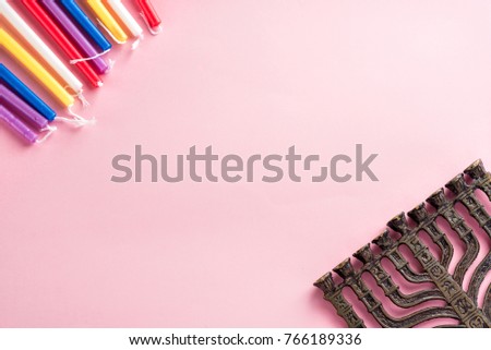 Image of jewish holiday Hanukkah  colorful candles, vintage bronze menorah (traditional Candelabra) on pink background.Flat lay.Copy space for text.