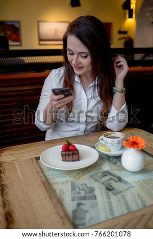 young brunette woman sitting in café in interior making order menu make picture photo of food eating talking by phone taste new dish typing message, hungry