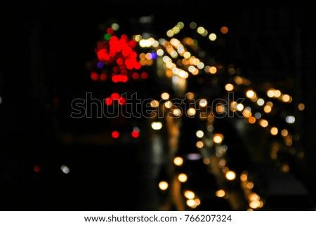 Car's headlights on defocused photo of night street. Blurred Defocused Lights of Heavy Traffic.