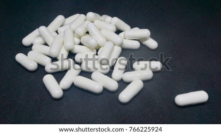 Group of white medicine capsules for anti pain in black background.
