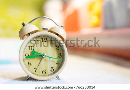 The wooden alarm clock is on the table