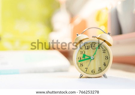 The wooden alarm clock is on the table