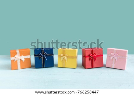 Small Gift box on wood table on pastel green color background with copy space. Christmas, New Year or Valentine celebration holiday concept. Use for your greeting card or web design.