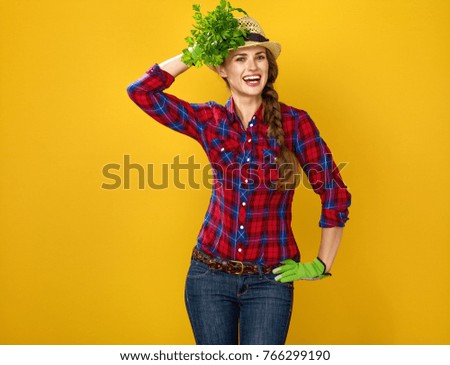 Healthy food to your table. Portrait of smiling modern woman grower in checkered shirt on yellow background using fresh parsley as an accessory