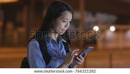 Woman watching on mobile phone in city at night