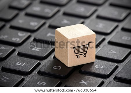 Wooden block with shopping cart graphic on laptop keyboard. 3D illustration. Online shopping concept. 