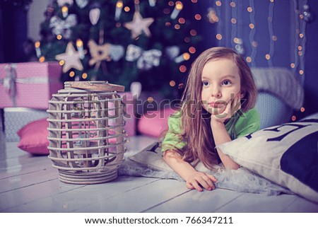 The girl lies near Christmas tree