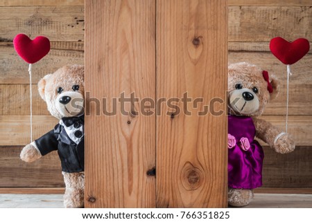 A photo of cute teddy bear holding heart-shaped balloon with wood board texture