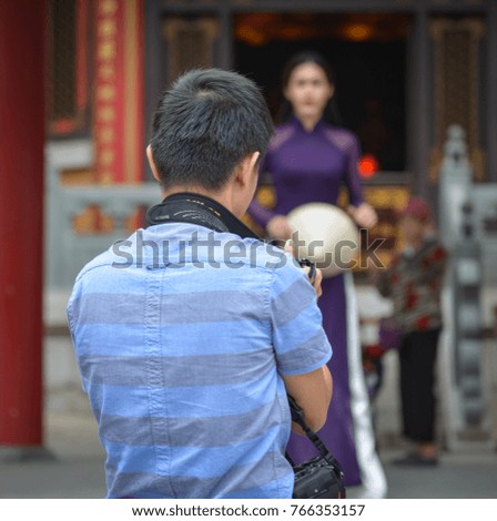 A photographer taking pictures of a beautiful woman in Chinese Buddhist temple.