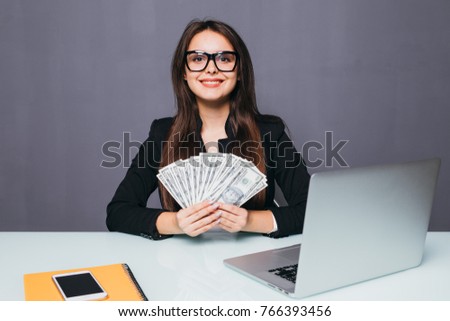 Portrait of business woman with money in hands at work place with laptop