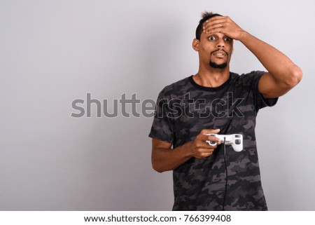 Studio shot of young bearded handsome African man against gray background