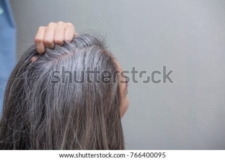 woman is checking white hair white looking at the mirror