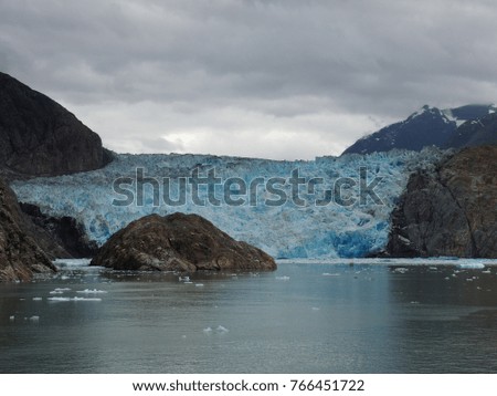 The face of Sawyer glacier with blue glacier ice and brown rock cliff while traveling in the serene attraction of Tracy Arm Fjord