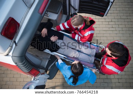 top view of paramedic team moving man on ambulance stretcher into car Royalty-Free Stock Photo #766454218