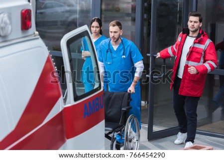 paramedics moving wheelchair from hospital to ambulance