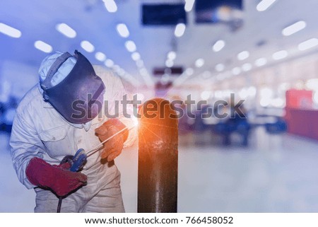 worker welding steel pipe in factory on bokeh background