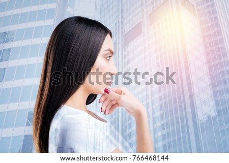 Young beauty. Attractive female person touching her chin while looking forward and standing in semi position
