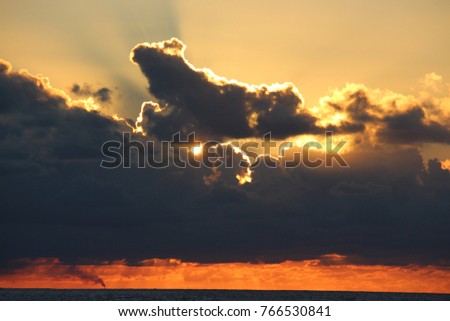 A picture of Sunset with thick clouds above the ocean 