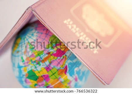Globe covered with Russian passport  in the sunlight. Toned