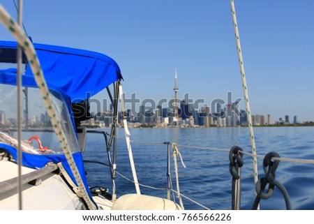 View of the Toronto city skyline from the deck of a sailboat in Toronto Harbour on a bright sunny day with blue skies.