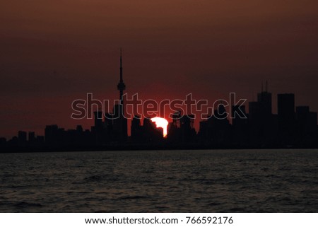Sunset silhouette of Toronto City Skyline from the water.