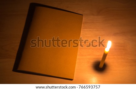 Candle light with note book on the wooden table in the dark night. picture for art work design or add text message.