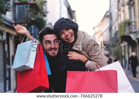 A couple of young engaged or friends, while they are shopping, having fun together, play and take pictures while they smile. Concept of: shopping, entertainment, friendship, love and leisure.