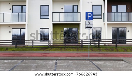 Empty car parking for the disabled next to a new modern uninhabited house. Urban mass production buildings. Panoramic collage from several outdoor photos. 