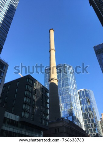 New York City low angle photo of huge chimney pipe surrendered by high rise new buildings on Upper west side of Manhattan