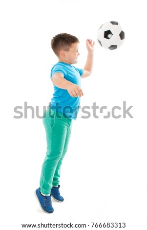  Full length portrait of a child in sportswear jogging with a soccer ball. Isolated on white background