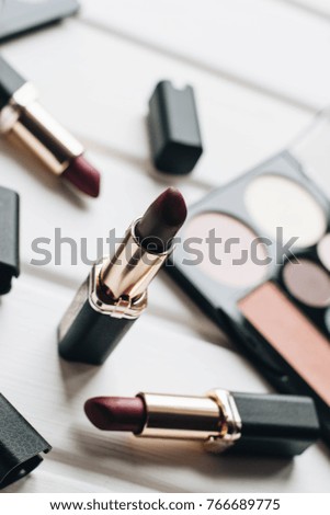 Lipsticks of different colors and eyeshadows on wooden background 