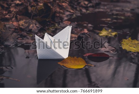 White paper boat and fallen autumn leaves. Autumn sadness
