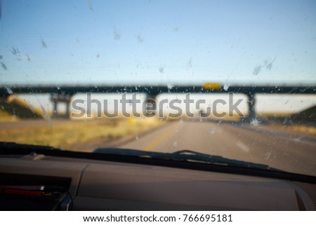 Dead bugs splattered on the windscreen of a car killed by impact with the glass while driving as the vehicle approaches on overpass bridge Royalty-Free Stock Photo #766695181